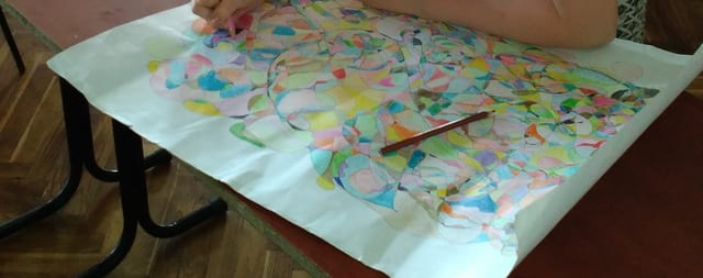 Veliki pastelni fraktal na papiru preko školske klupe, sa olovkom položenom preko crteža.